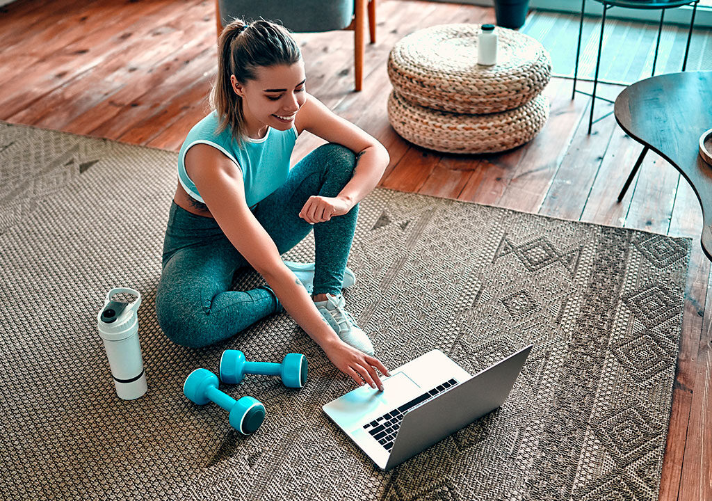 Mujer que usa la computadora portátil mientras hace ejercicio