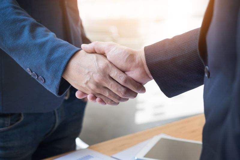 Dos hombres de negocios estrechándose las manos durante una reunión en la oficina éxito trato saludo y concepto de socio
