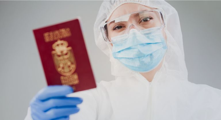 Doctora con equipo de bioseguridad sosteniendo un pasaporte